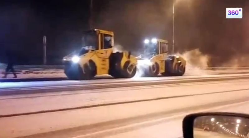 Рабочие укладывают асфальт поверх снега на федеральной трассе в Подмосковье